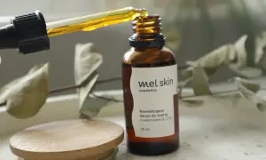 Kropla złotego serum z pipety wpada do brązowej buteleczki Mel Skin.