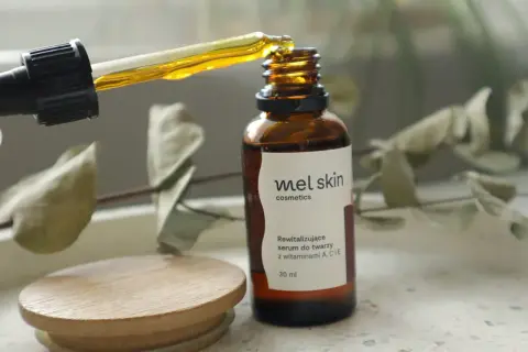 Kropla złotego serum z pipety wpada do brązowej buteleczki Mel Skin.